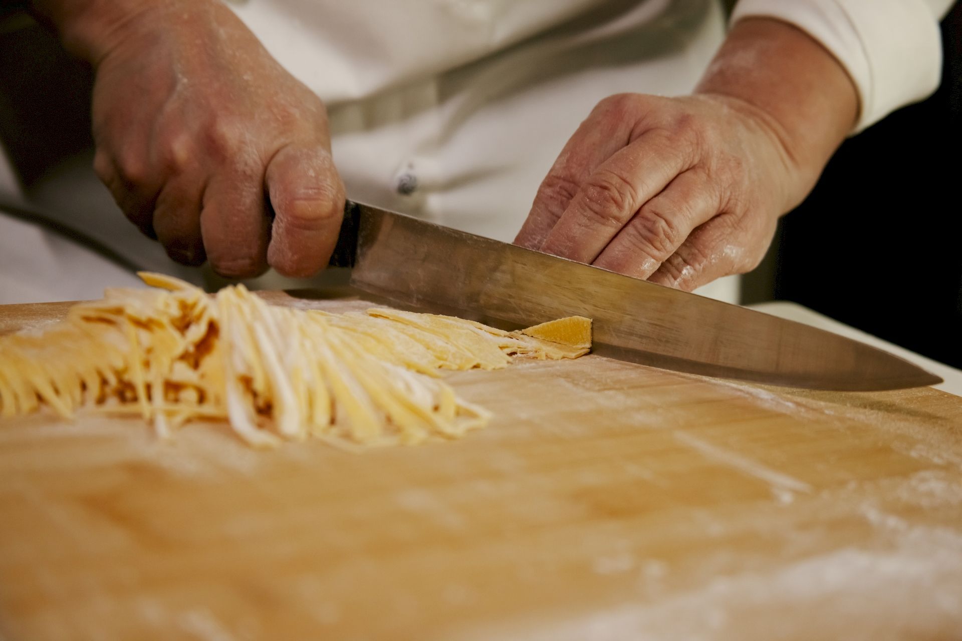 Aurora chef mentre taglia la massa durante preparazione piatto Tricolore fettuccine all'uovo di spinaci con funghi e tartufo del Ristorante La Tacchinella di Canzano a Teramo in Abruzzo